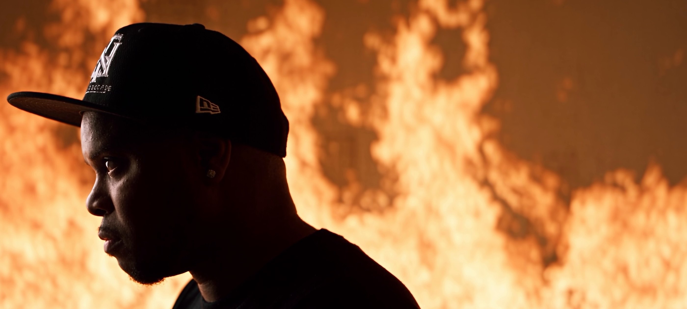 Dinero Montaro in front of a wall of fire